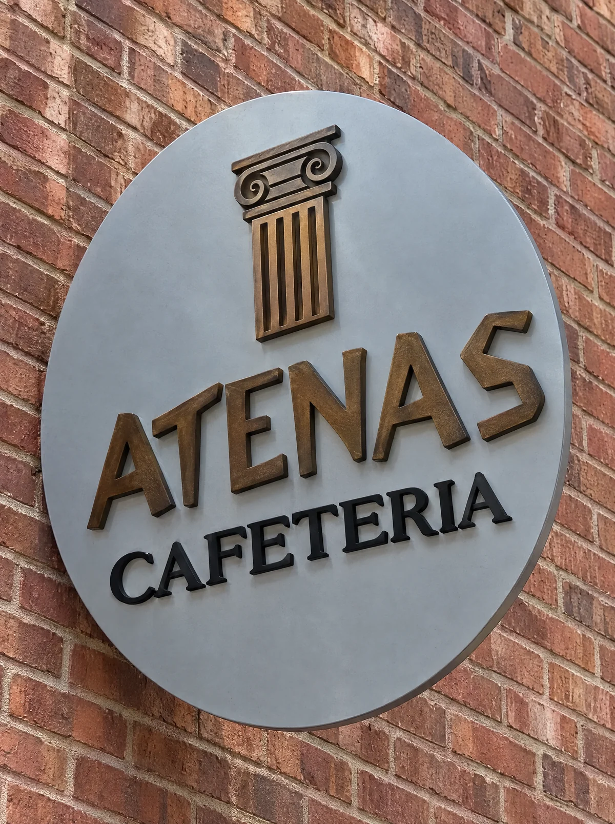 El rótulo de Atenas Cafetería en la fachada, con la columna jónica y las letras en bronce